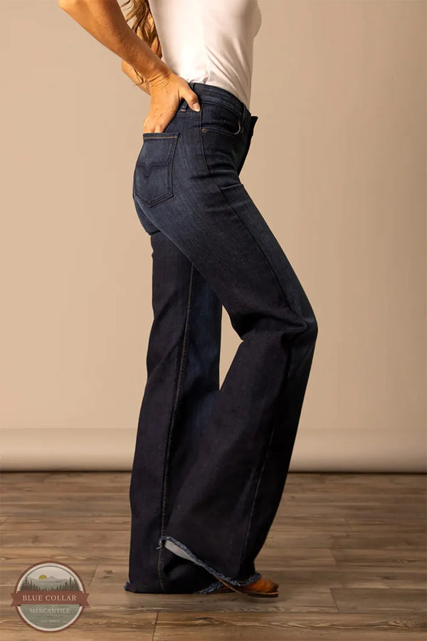 Person wearing dark blue jeans standing against a beige wall. Kimes Ranch WJE0000016 Olivia dark wash side