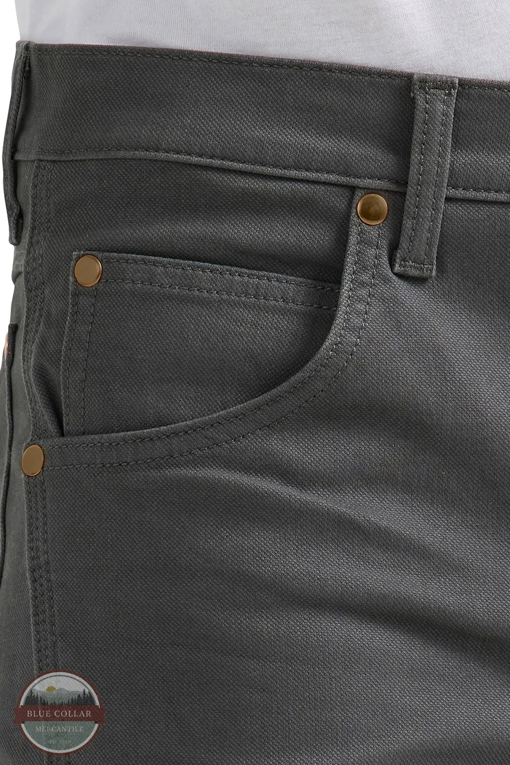 Close-up of gray pants with gold buttons and a visible brand logo. Wrangler 112361474 Premium Performance Tough Comfort Cowboy Cut Slim Fit Canvas Jean in Grey Pinstripe front pocket view