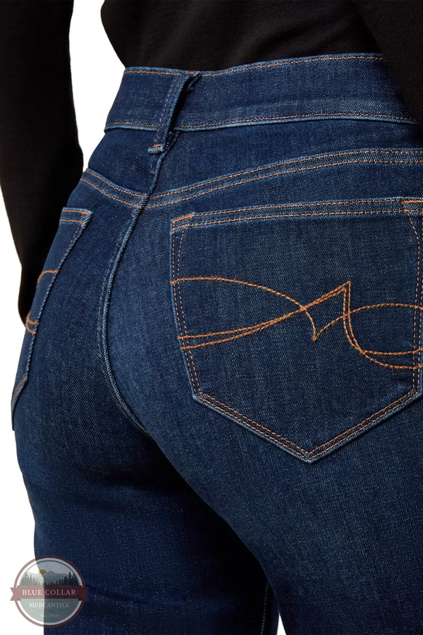 Ariat 10079195 Women's Perfect Rise Vilma Ultrastretch Trouser Jeans in Hayward, Close-up of the back waist and rear pocket of dark blue denim jeans with contrast orange stitching and a butterfly logo on the pocket, worn with a black top.