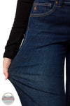 Ariat 10079195 Women's Perfect Rise Vilma Ultrastretch Trouser Jeans in Hayward, Close-up of a person wearing dark blue denim jeans, pulling the fabric outward with one hand to show stretch. A black long-sleeve top is visible, and a small orange 'A' logo appears on the pocket.