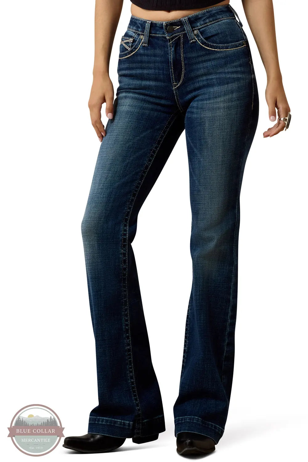 Ariat 10079240 Women's High Rise Teresa Slim Trouser Jeans in Decatur, A model wearing a pair of dark blue bootcut jeans with a slight flare at the hem, paired with black shoes, shown from the waist down on a white background.