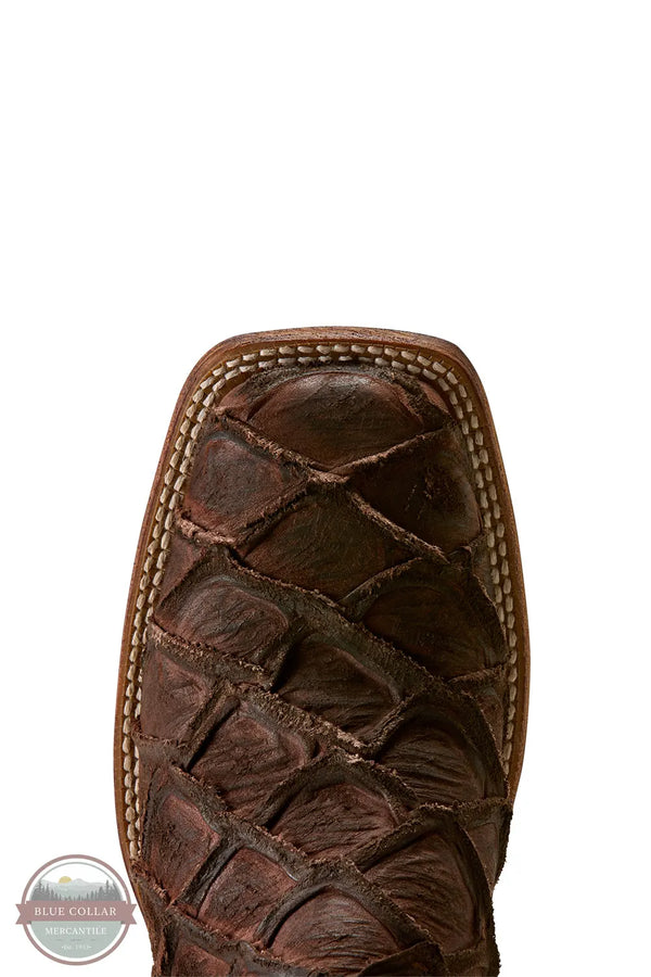 Ariat's 10080345 Men's Riverside Exotics Print Square Toe Western Boot in Chocolate Bass Print / Indigo Honor Blue, Close-up of the toe and upper vamp of a dark brown western boot featuring a crocodile or alligator-textured leather toe cap and contrast stitching, shown on a white background.