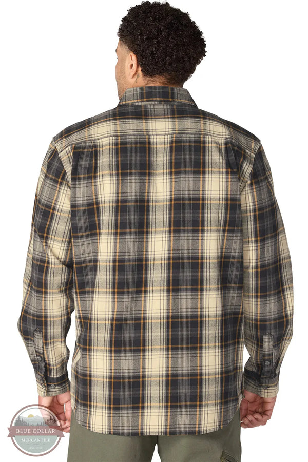Carhartt 107013-N04 Men's Hubbard Loose Fit Long Sleeve Flannel Plaid Shirt, A man viewed from the back wearing a long-sleeve plaid button-up shirt in beige, navy, and brown tones, paired with olive green pants against a white background.