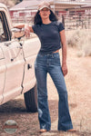 Wrangler 112382765 Women's Bespoke High Rise Trouser Jean in Reina lifestyle image of woman in jeans leaning on truck