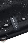 Under Armour 1365918 UA Men's Storm Beanie, Close-up of a black textured fabric item with water droplets on the surface and a dark gray woven label reading STORM.