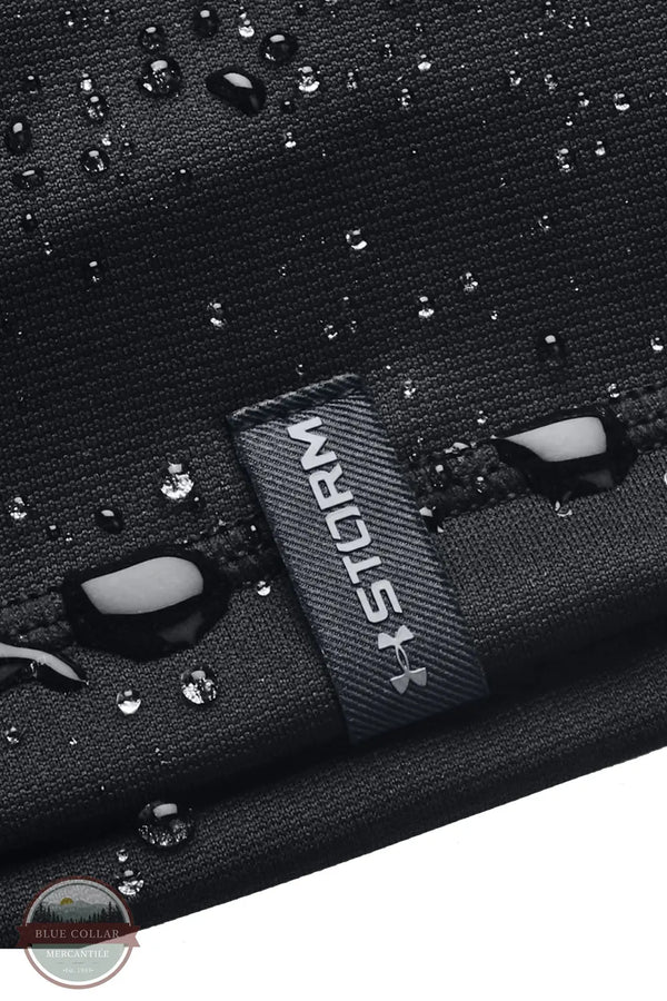 Under Armour 1365918 UA Men's Storm Beanie, Close-up of a black textured fabric item with water droplets on the surface and a dark gray woven label reading STORM.