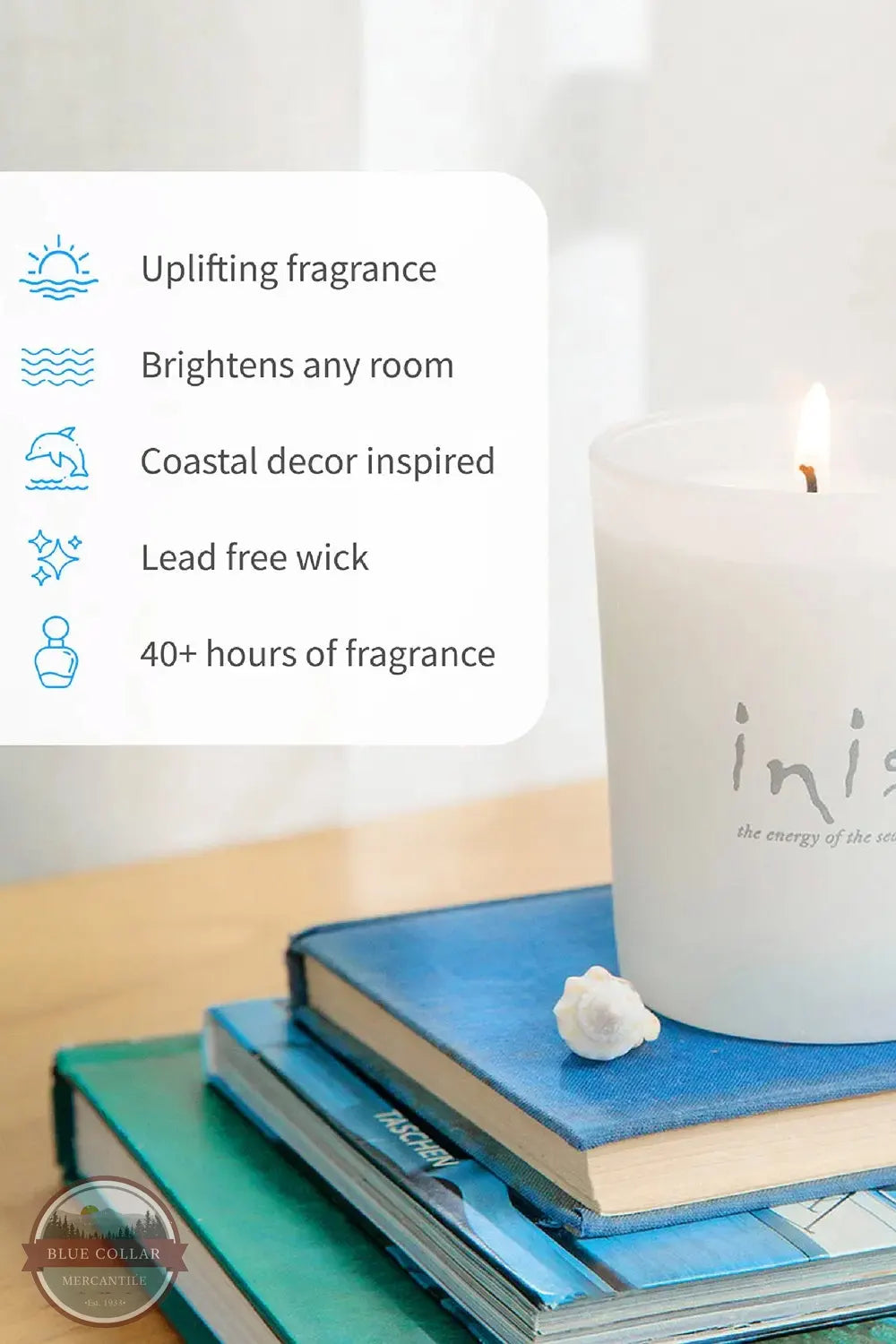 Inis 8017185 Scented Candle 6.7 oz., A white scented candle with a lit flame sits on top of stacked blue books, with a small white flower beside it. A text panel on the left lists product benefits: uplifting fragrance, brightens any room, coastal decor inspired, lead free wick, and 40+ hours of fragrance.