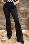 Judy Blue 881177REG High Waist Black Jaqueline Flare Jean With Lace, Black flare jeans with lace-up detailing on the outer sides, shown on a model standing on a cowhide rug against a rustic wood plank wall.