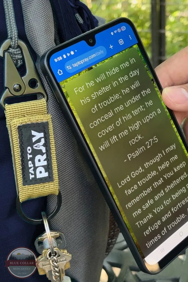 Versible's 100-554 Tap To Pray® Moss Camo Tactical Carabiner Keychain shown clipped to backpack, tapping phone for prayer