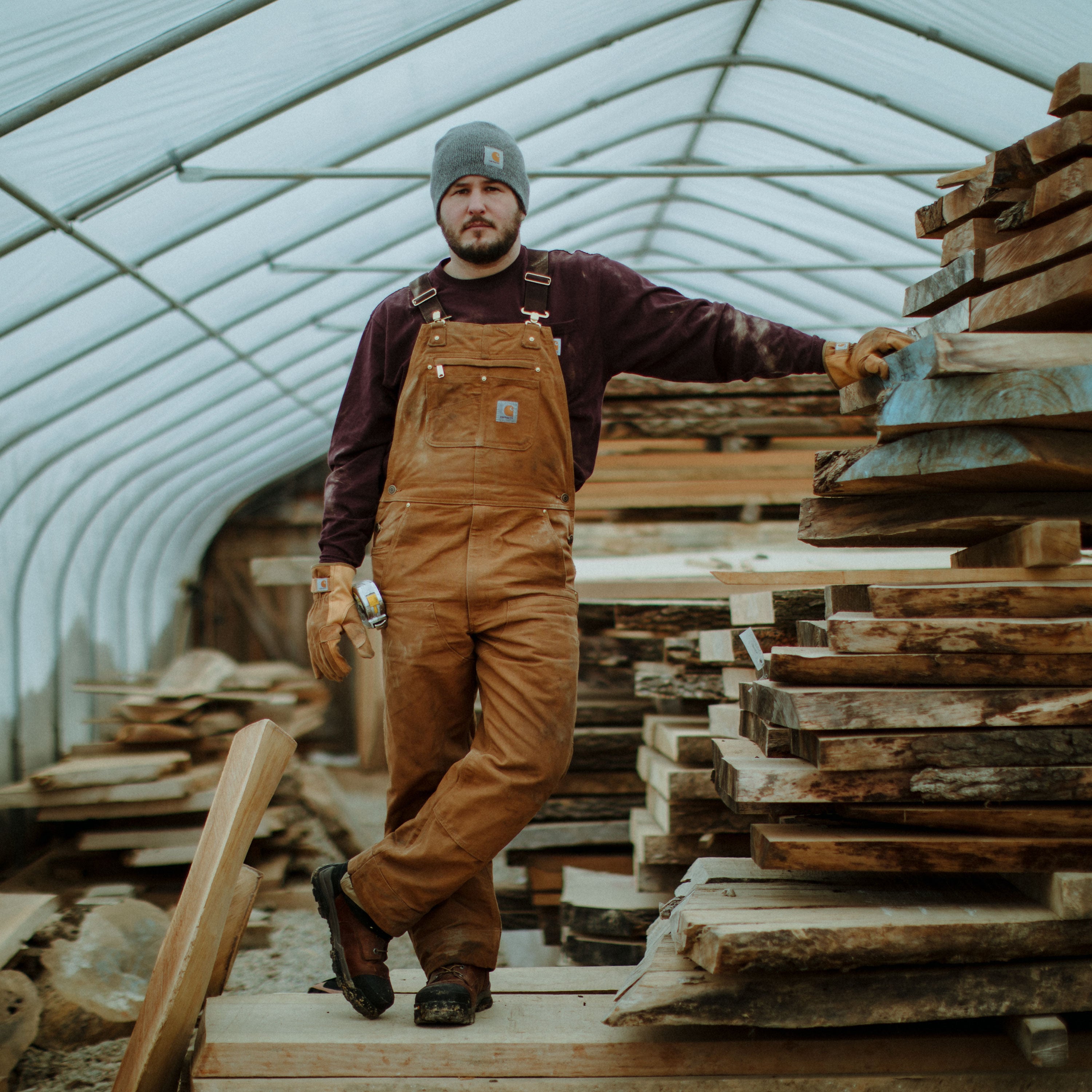 Carhartt 102776-211 Relaxed Fit Duck Bib Overall in Carhartt Brown image of worker wearing it