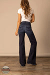 Woman wearing dark blue flared jeans and a white shirt against a beige wall. Kimes Ranch WJE0000016 Olivia dark wash rear