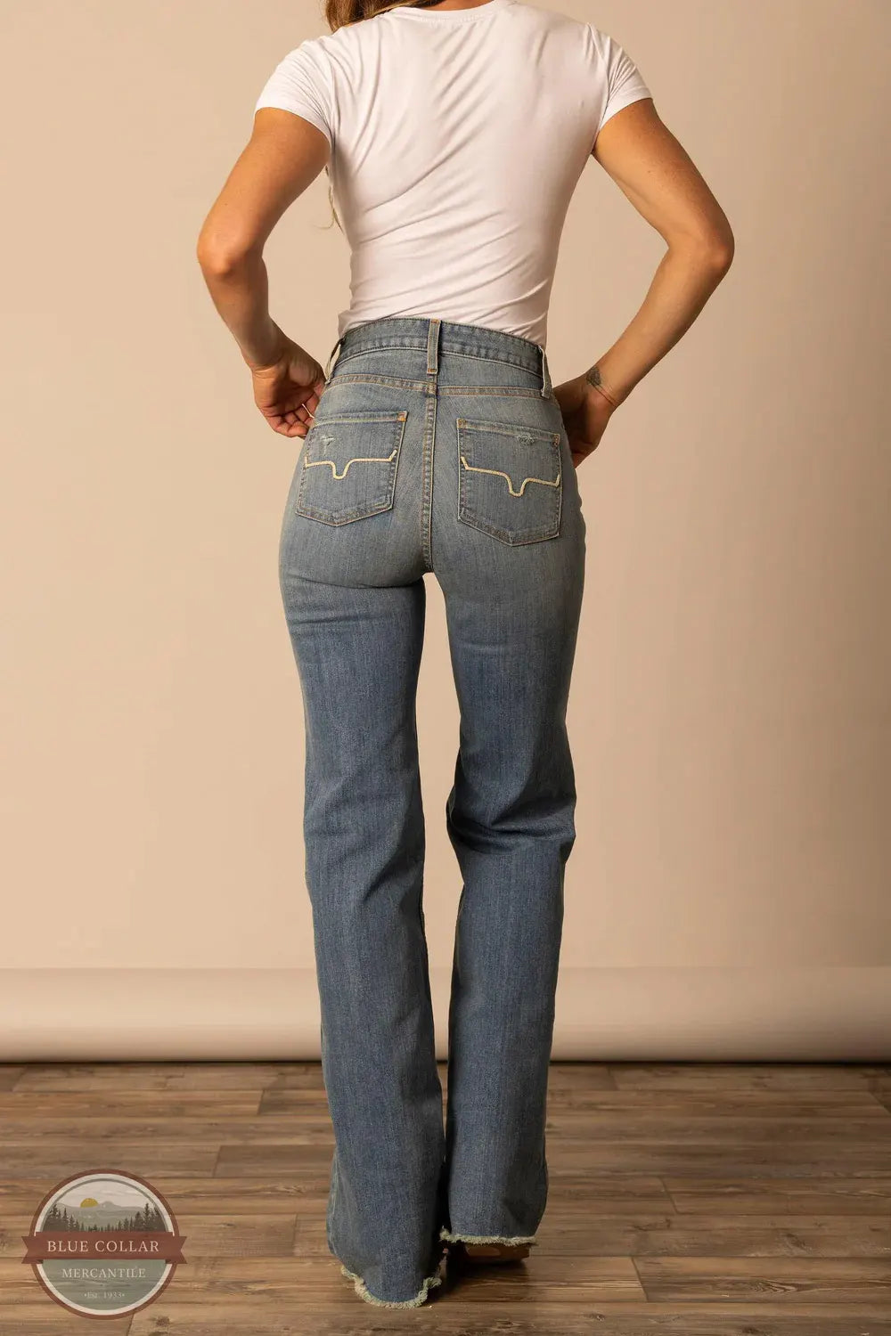 Person wearing blue jeans and a white t-shirt against a beige wall. Kimes Ranch WJE0000016 Olivia light wash rear