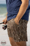 Local Boy Outfitters L1600015-BLD Men's Volley 6" Shorts in Mossy Oak Bottomland Camo lifestyle image of man fishing